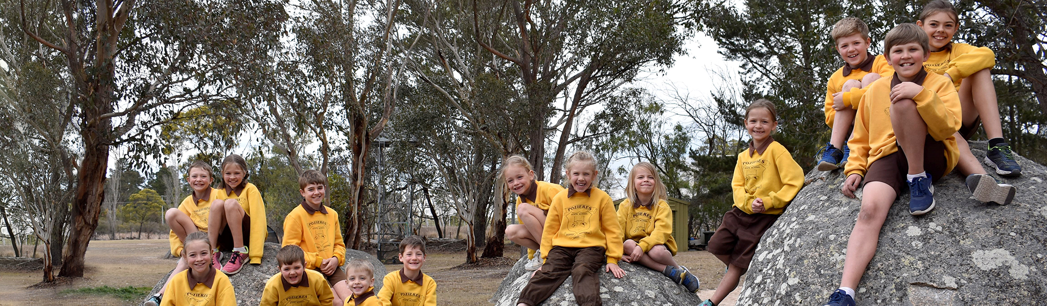 Students in uniform sitting on boulders at Pozieres State School